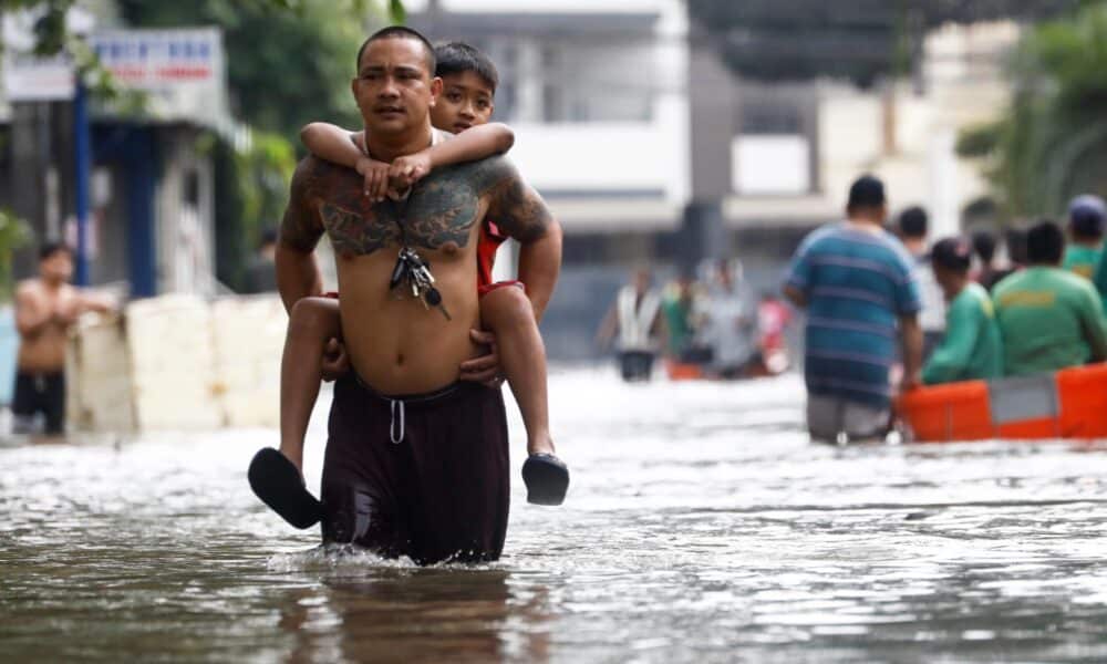 Un hombre lleva a hombros a su hijo este viernes en una calle inundada en la localidad de Cainta, unos 30 kilómetros al este de Manila, tras el paso de la tormenta Trami por el norte de Filipinas. EFE/EPA/ROLEX DELA PENA