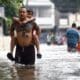 Un hombre lleva a hombros a su hijo este viernes en una calle inundada en la localidad de Cainta, unos 30 kilómetros al este de Manila, tras el paso de la tormenta Trami por el norte de Filipinas. EFE/EPA/ROLEX DELA PENA