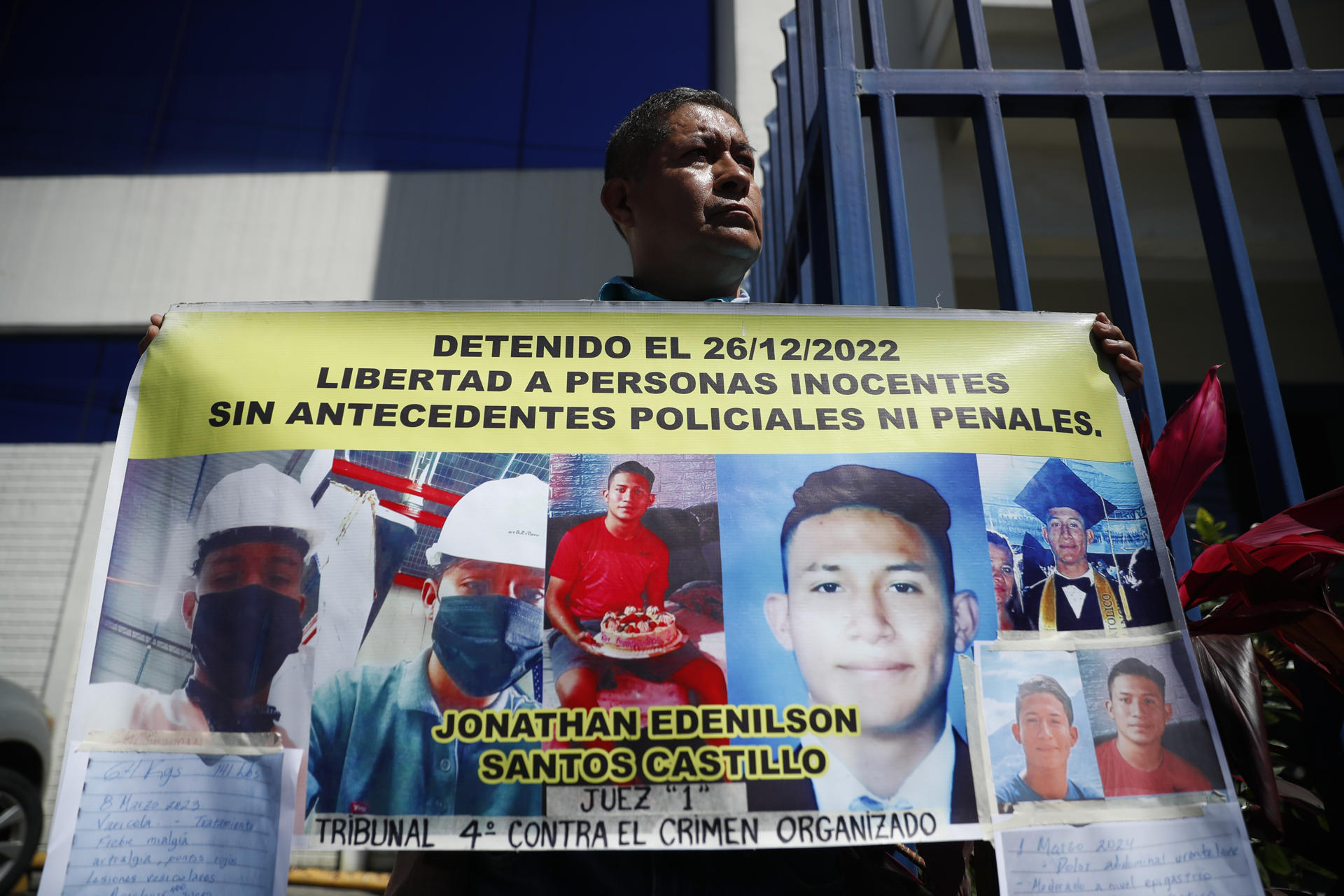 Fotografía de archivo de un familiar de un joven detenido bajo el régimen de excepción en El Salvador, que muestra una pancarta a las afueras de una sede de la Fiscalía General, en Antiguo Cuscatlán (El Salvador). EFE/ Rodrigo Sura