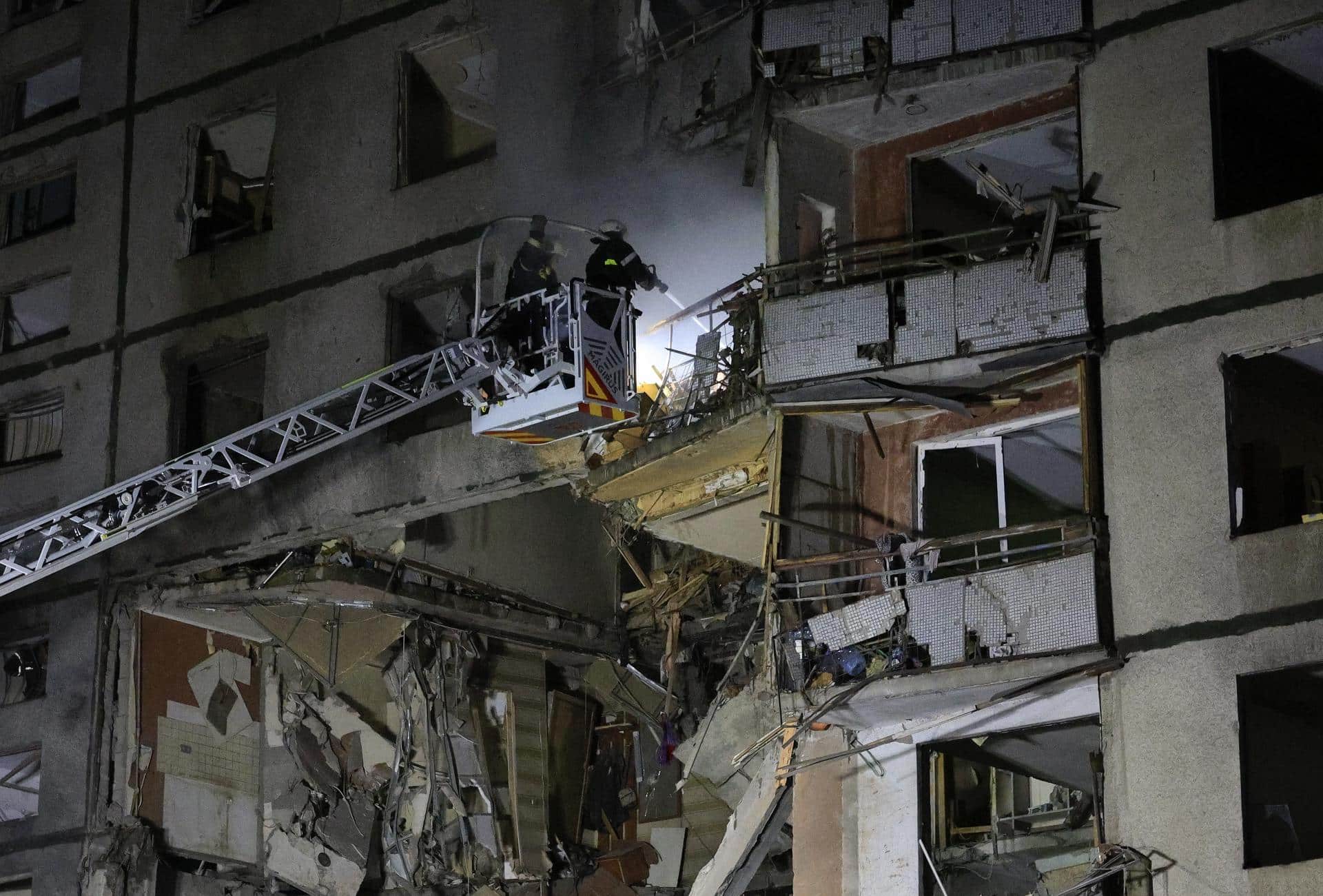 Los equipos de rescate trabajan en el lugar de un ataque ruso con bombas aéreas guiadas que destrozó parcialmente un edificio de viviendas de la ciudad de Járkov, a altas horas de la noche. EFE/EPA/SERGEY KOZLOV