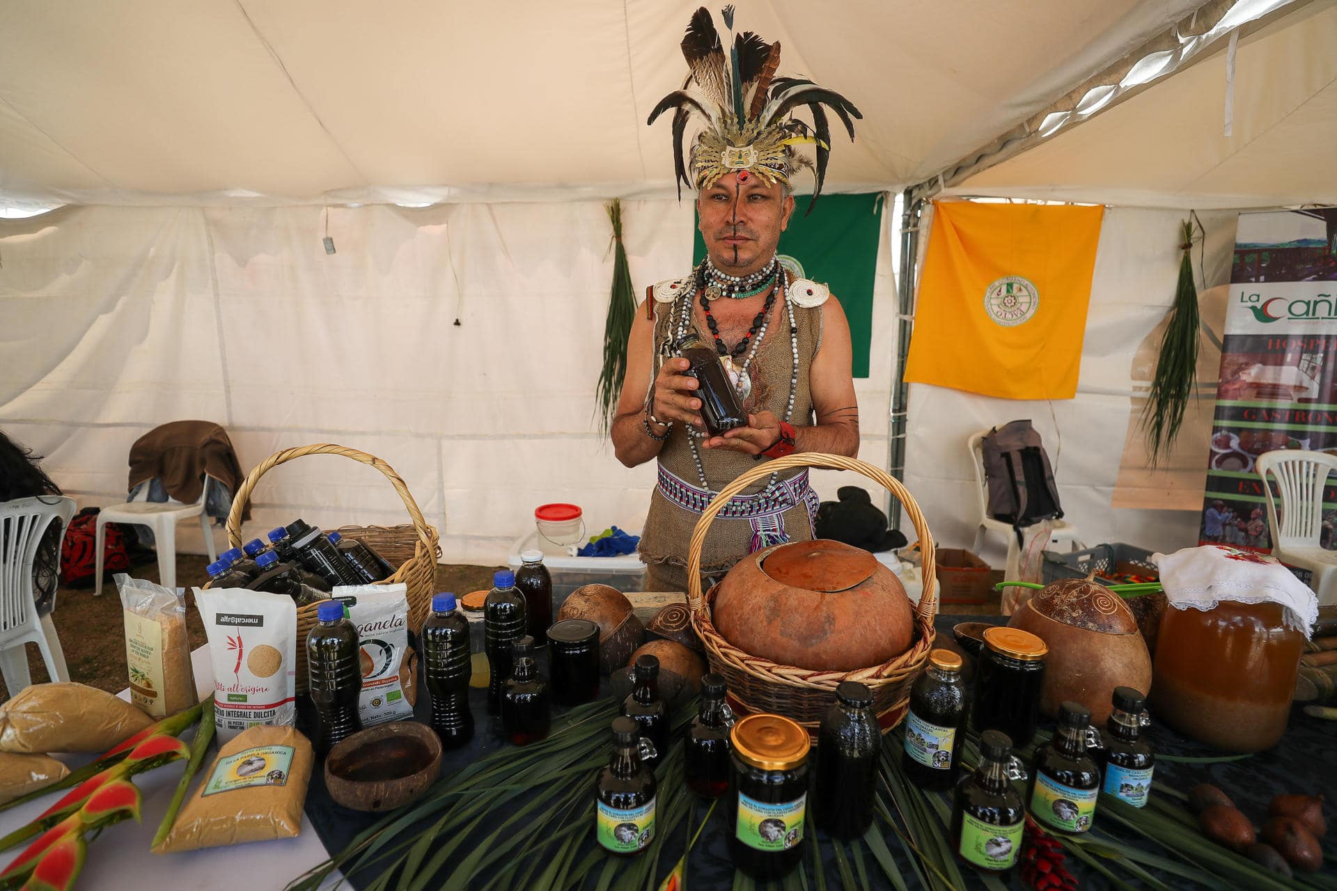 Un hombre con un traje típico de indígena Yumbo vende productos orgánicos, durante el séptimo Festival del Chocó Andino, el 12 de octubre de 2024, en la población de Calacalí, al noroccidente de Quito (Ecuador). EFE/ José Jácome