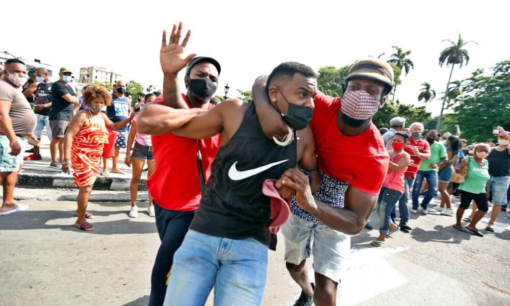 Fotografía de archivo de dos personas deteniendo a un hombre durante una manifestación en La Habana (Cuba), en el estallido social del 11 de julio de 2021 (11J). EFE/ Ernesto Mastrascusa