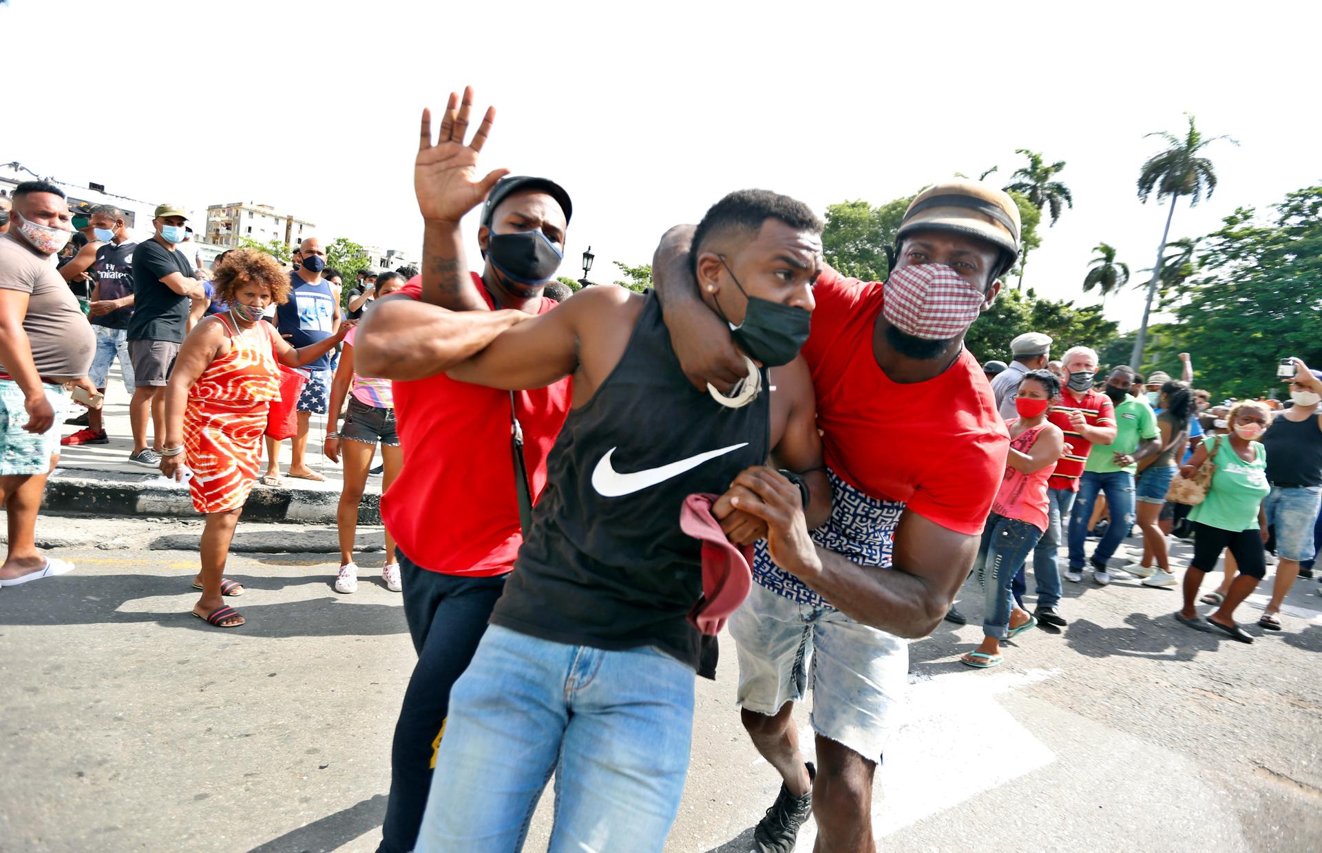 Fotografía de archivo de dos personas deteniendo a un hombre durante una manifestación en La Habana (Cuba), en el estallido social del 11 de julio de 2021 (11J). EFE/ Ernesto Mastrascusa