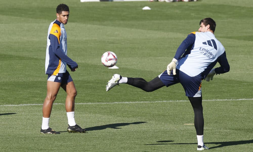 Thibaut Courtois (d) despeja el balón en presencia del centrocampista inglés Jude Bellingham. El portero belga ha sido incluido en la convocatoria para el partido ante el Celta de Vigo. EFE/Juan Carlos Hidalgo