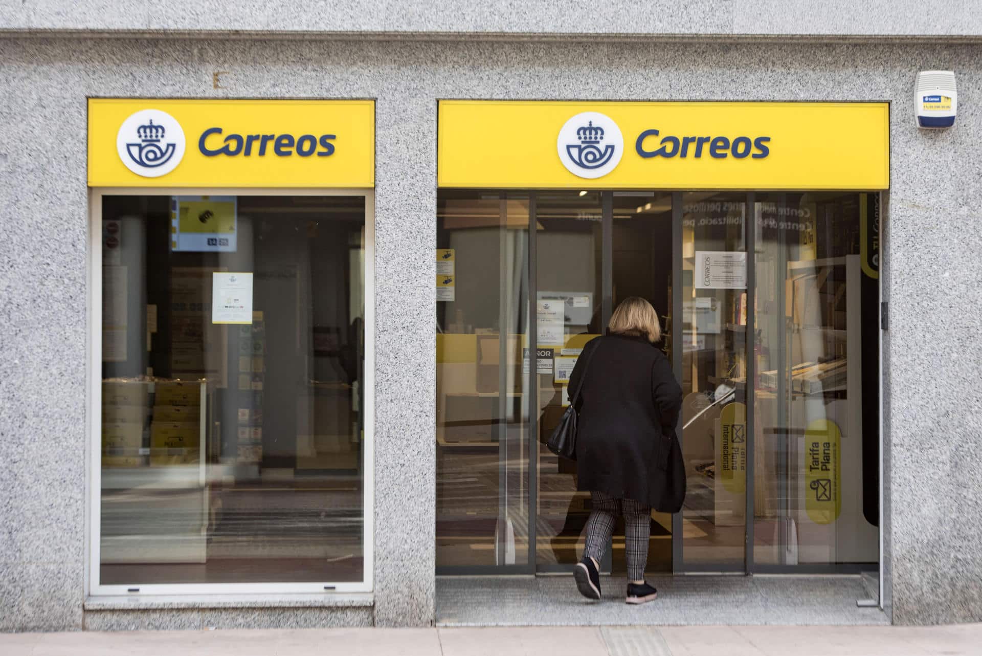 Una mujer entra en una oficina de Correos. EFE/ARCHIVO/ David Arquimbau Sintes