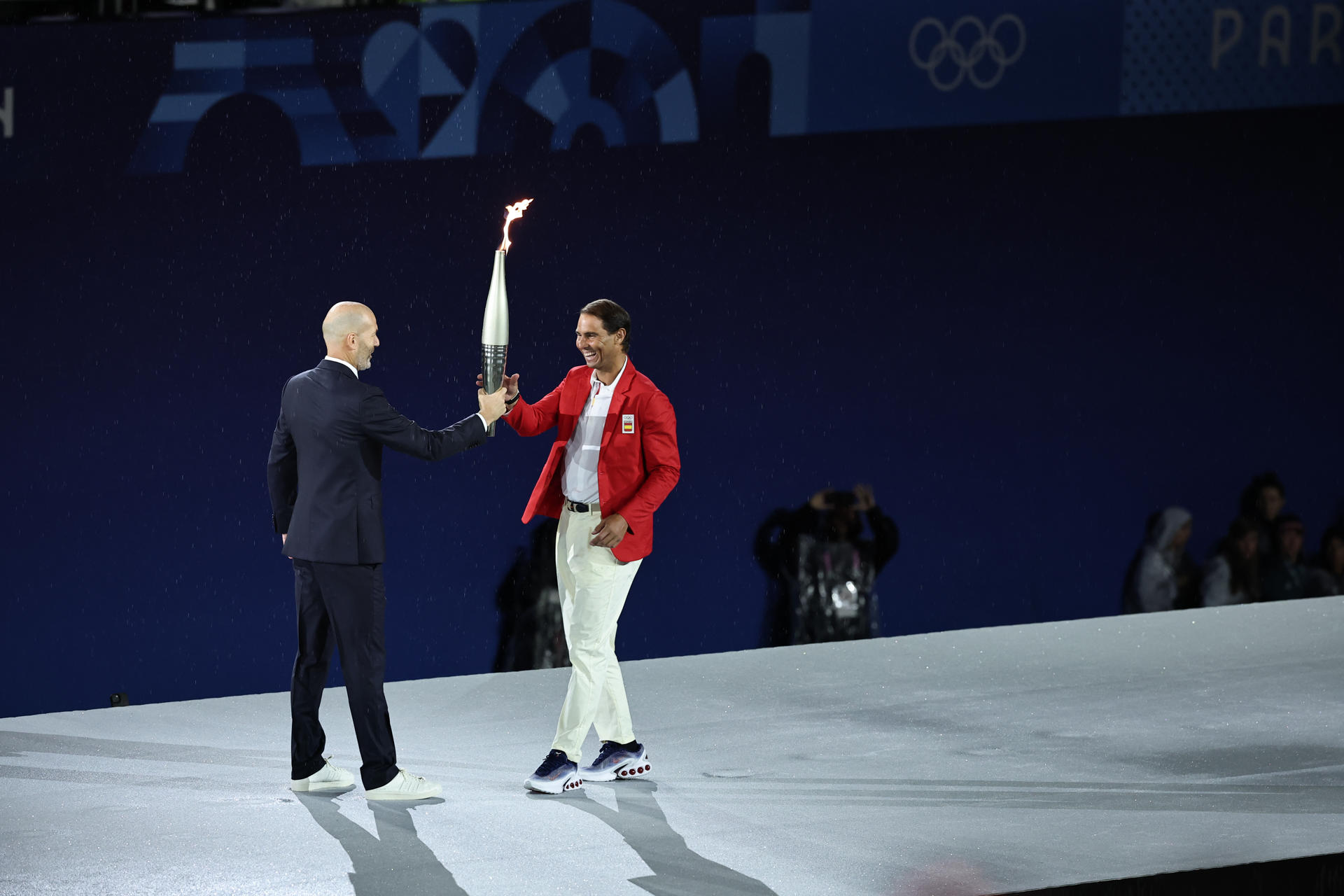 El tenista español Rafa Nadal (d) recoge la antorcha olímpica de manos del exfutbolista Zinedine Zidane en la Plaza del Trocadero durante la ceremonia de inauguración de los Juegos Olímpicos de París 2024. EFE/ Christophe Petit Tesson POOL/Archivo