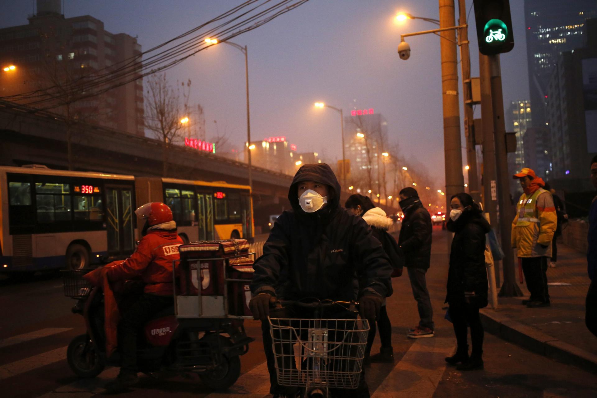 En la imagen de archivo, peatones utilizan mascarillas para protegerse de la contaminación en Pekín (China). EFE/How Hwee Young