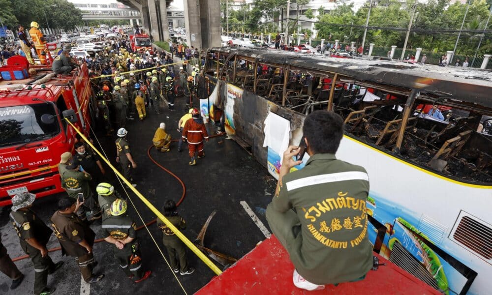 Los equipos de emergencia inspeccionan el autobús calcinado en el norte de Bangkok, que transportaba a estudiantes y profesores.
EFE/EPA/NARONG SANGNAK