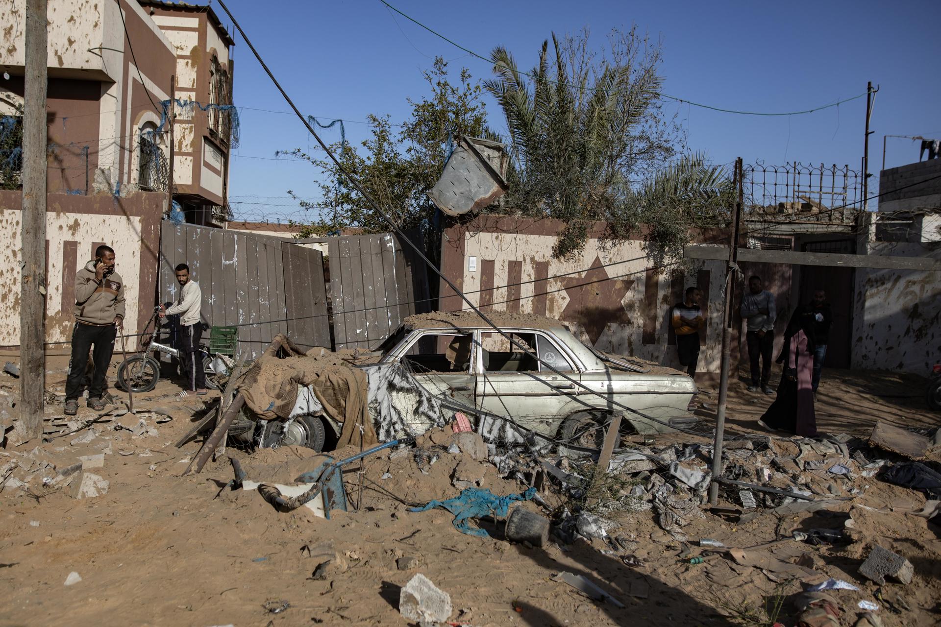 Foto de archivo de unos palestinos junto a un automóvil dañado tras los ataques aéreos israelíes en Jan Yunis, en el sur de la Franja de Gaza. EFE/EPA/HAITHAM IMAD