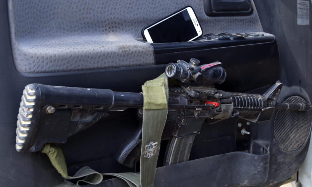 Un rifle de asalto M-16 y un teléfono móvil en la puerta de un vehículo de un militar israelí en una zona próxima a la frontera con Gaza, en una imagen de archivo.EFE/Jim Hollander