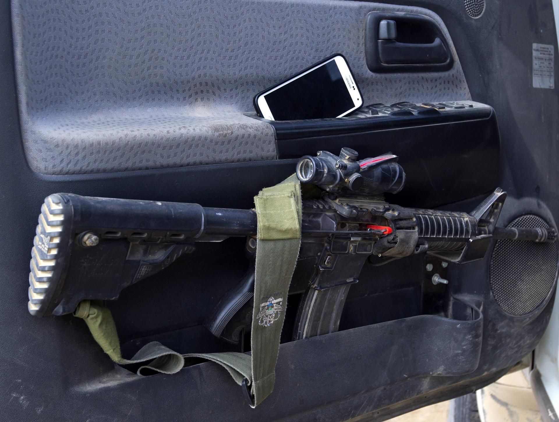 Un rifle de asalto M-16 y un teléfono móvil en la puerta de un vehículo de un militar israelí en una zona próxima a la frontera con Gaza, en una imagen de archivo.EFE/Jim Hollander