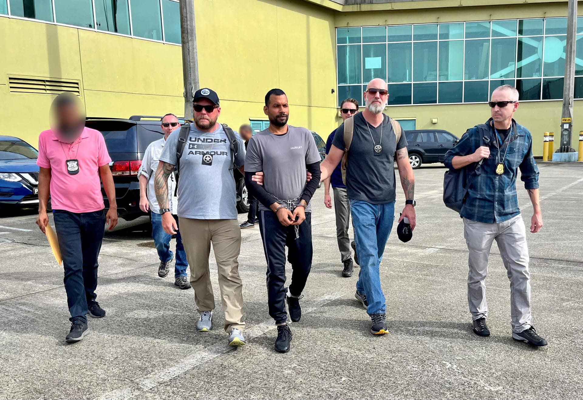 Fotografía cedida sin fecha por la Embajada de Estados Unidos en Trinidad y Tobago, donde aparecen alguaciles estadounidenses, agentes del Servicio de Policía de Trinidad y Tobago y del Servicio de Seguridad Diplomática de Estados Unidos escoltando a Farzan Mohammed (c) para su extradición a Estados Unidos por delitos sexuales contra niños, en el aeropuerto de Piarco (Trinidad y Tobago). EFE/ Embajada de Estados Unidos /SOLO USO EDITORIAL /NO VENTAS /SOLO DISPONIBLE PARA ILUSTRAR LA NOTICIA QUE ACOMPAÑA /CRÉDITO OBLIGATORIO