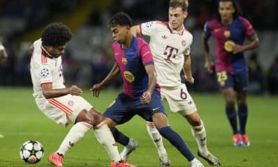 El delantero del FC Barcelona Lamine Yamal (c) se escapa del defensa del Bayern Joshua Kimmich (d), durante el encuentro correspondiente a la fase regular de la Liga de Campeones que disputan hoy miércoles FC Barcelona y Bayern Munich en el estadio Olímpico Lluis Companys, en Barcelona. EFE/Alejandro García.