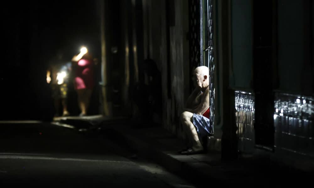 Un hombre observa durante un apagón en La Habana, (Cuba). Cuando de verdad se sufre el apagón es de noche. Cuando las casas quedan totalmente a oscuras, las cocinas eléctricas no sirven para preparar la cena, los ventiladores inertes no espantan el calor caribeño y solo las luces de un carro o un celular rompen el negro más rotundo. EFE/ Ernesto Mastrascusa