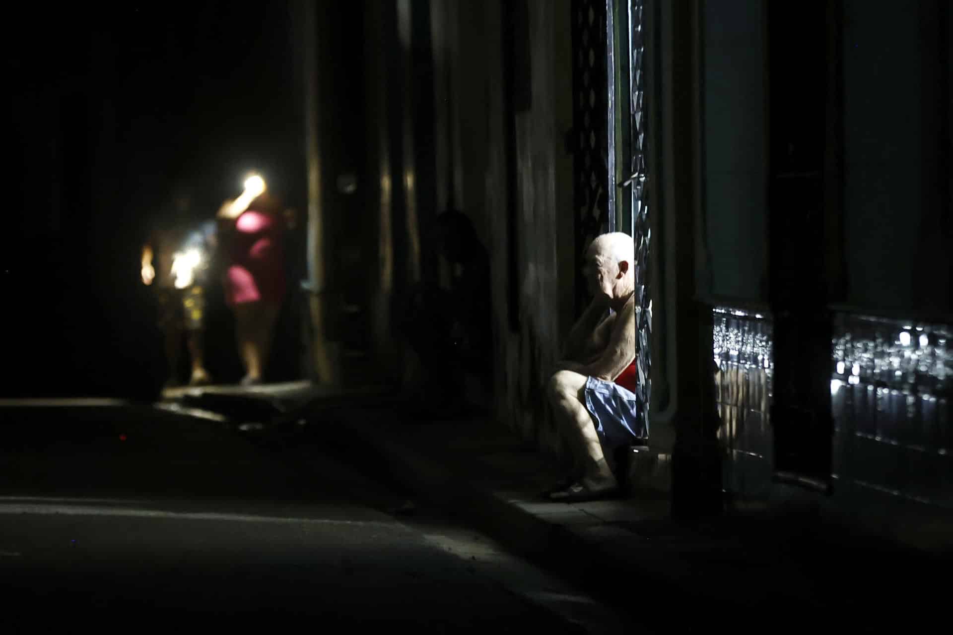 Un hombre observa durante un apagón en La Habana, (Cuba). Cuando de verdad se sufre el apagón es de noche. Cuando las casas quedan totalmente a oscuras, las cocinas eléctricas no sirven para preparar la cena, los ventiladores inertes no espantan el calor caribeño y solo las luces de un carro o un celular rompen el negro más rotundo. EFE/ Ernesto Mastrascusa