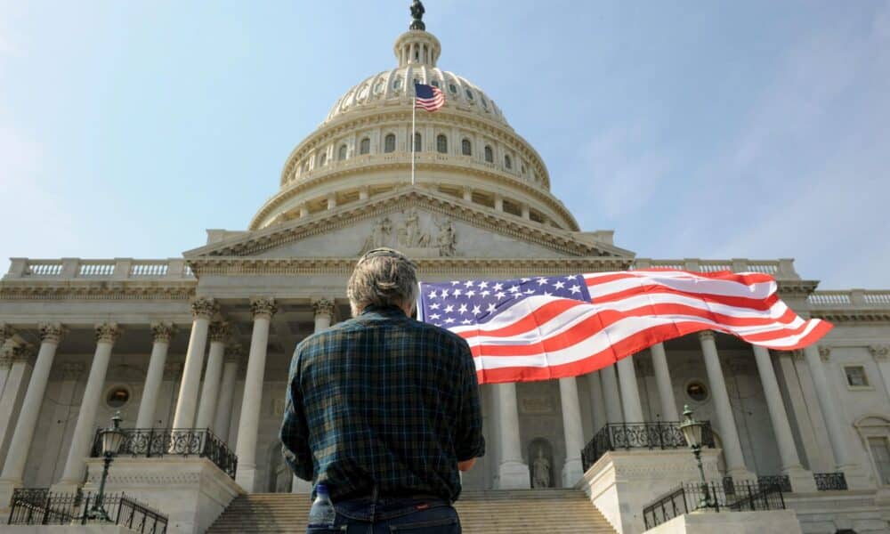 Un hombre con una bandera de los Estados Unidos delante del Capitolio en Washington, el 21 de marzo de 2010. EFE/MICHAEL REYNOLDS