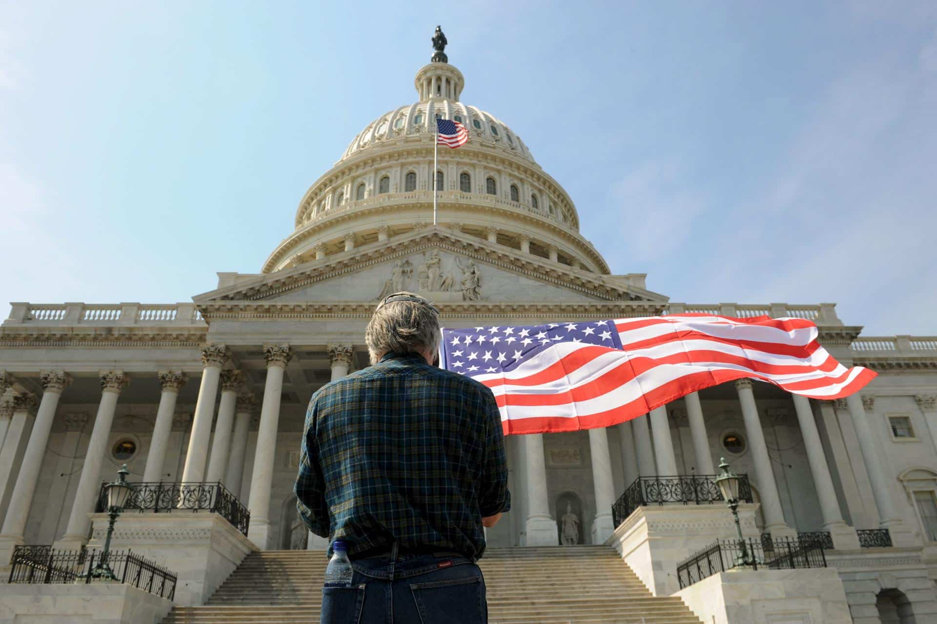 Un hombre con una bandera de los Estados Unidos delante del Capitolio en Washington, el 21 de marzo de 2010. EFE/MICHAEL REYNOLDS