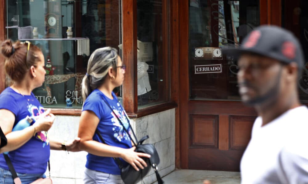 Personas caminan frente a una tienda cerrada por la falta de electricidad este viernes, en La Habana (Cuba). EFE/ Ernesto Mastrascusa