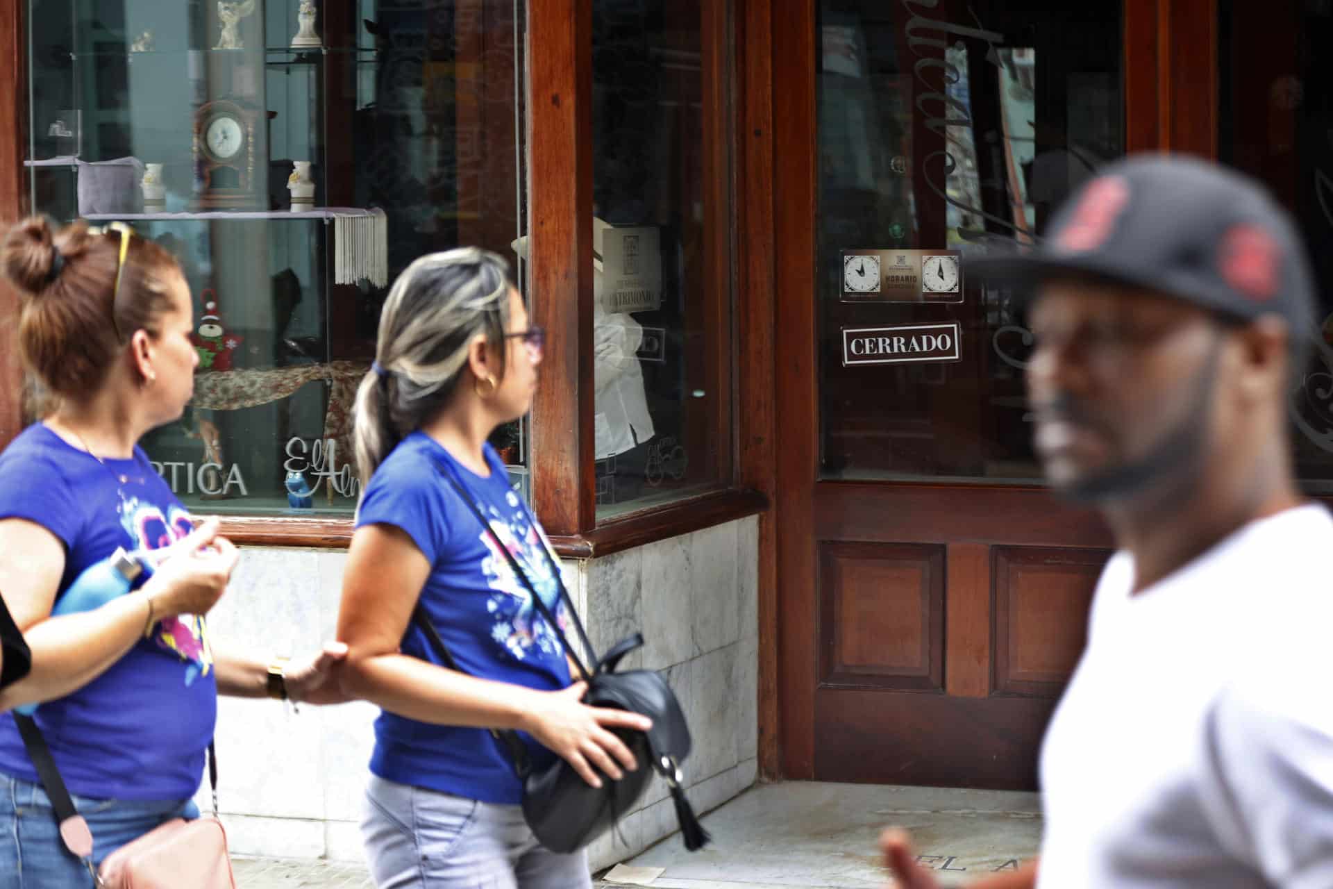 Personas caminan frente a una tienda cerrada por la falta de electricidad este viernes, en La Habana (Cuba). EFE/ Ernesto Mastrascusa