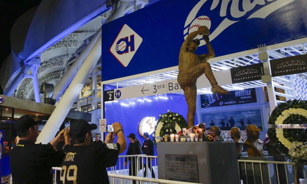 Aficionados colocan ofrendas en la estatua del beisbolista mexicano Fernando Valenzuela, este miércoles, en el estadio Panamericano de Béisbol, en Guadalajara (México). EFE/ Francisco Guasco