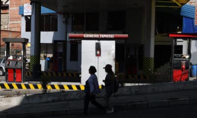 Mujeres caminan delante de una estación de servicio cerrada por falta de combustible este miércoles, en La Paz (Bolivia). EFE/Luis Gandarillas