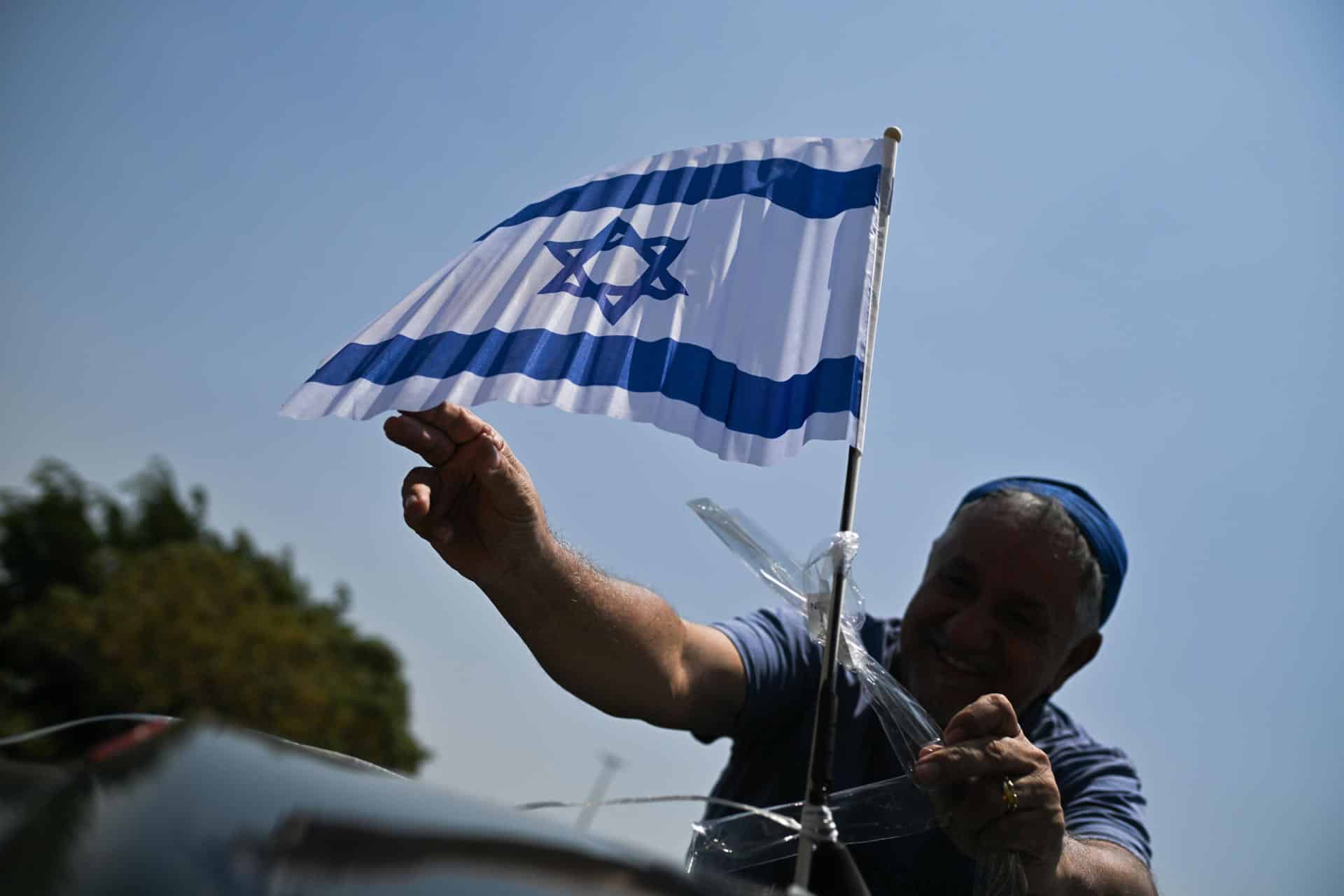 Un hombre sostiene una bandera de Israel durante una caravana en favor de la paz y el fin de la guerra, en vísperas del día en que se cumple un año del ataque de Hamas a Israel, este 6 de octubre de 2024, en Brasilia (Brasil). EFE/Andre Borges