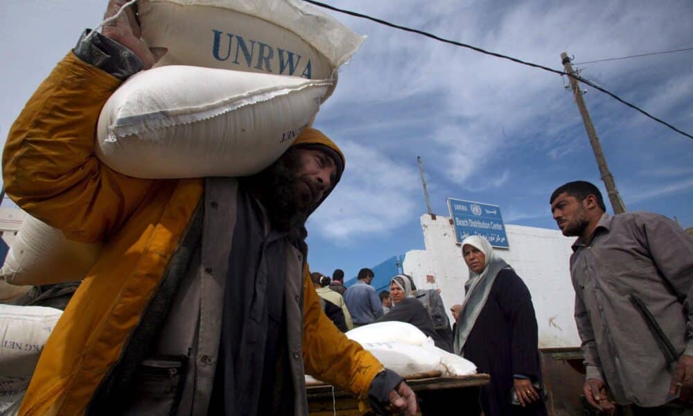 Fotografía de archivo que muestra a palestinos que recogen sacos de harina en el almacén de la agencia de la ONU para los refugiados palestinos (UNRWA) en el campo de refugiados de Shati, en Ciudad de Gaza. EFE/Ali Ali