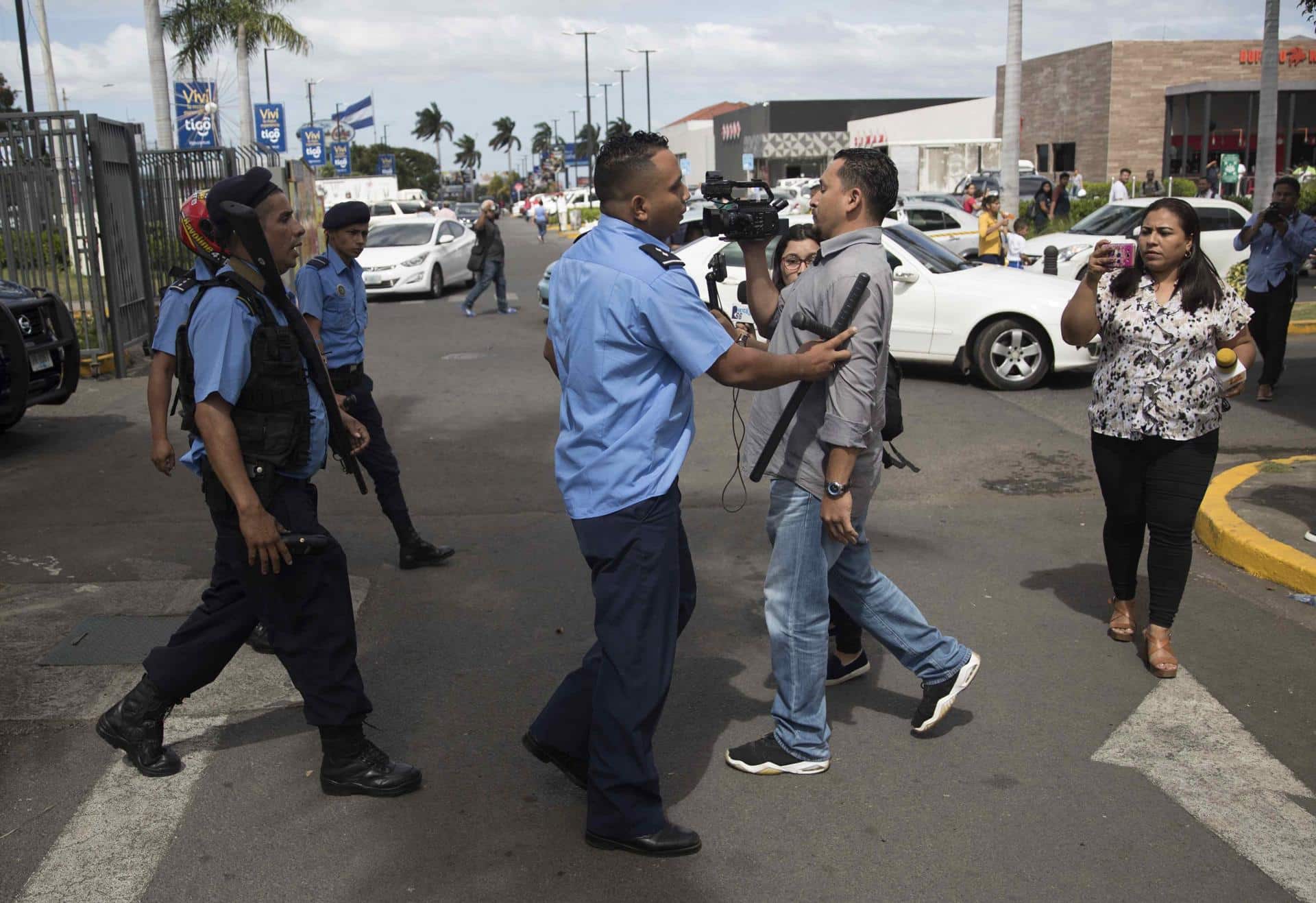 Fotografía de archivo del 12 de diciembre de 2019, en la que se observa a un agente de la Policía Nacional (c) obstruyendo el paso a un camarógrafo durante una protesta que exige la liberación de presos políticos, en Managua (Nicaragua).EFE/STR