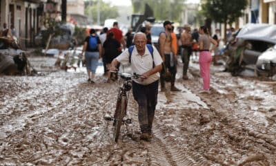 Un vecino de Paiporta atraviesa con su bicicleta una calle cubierta de barro, este jueves. EFE/Biel Aliño