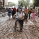 Un vecino de Paiporta atraviesa con su bicicleta una calle cubierta de barro, este jueves. EFE/Biel Aliño