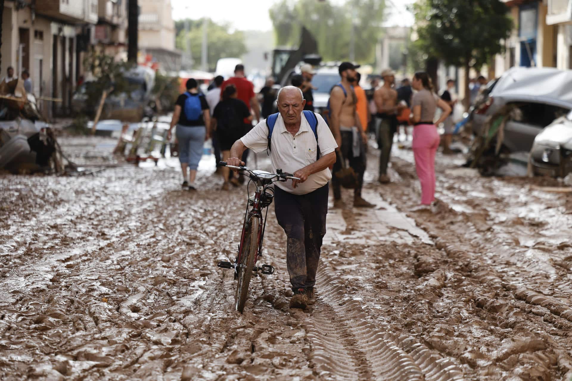 Un vecino de Paiporta atraviesa con su bicicleta una calle cubierta de barro, este jueves. EFE/Biel Aliño