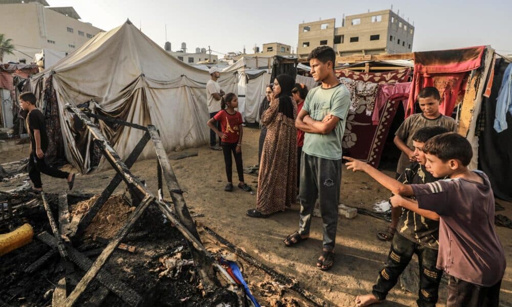 Niños ante los restos calcinados de unas tiendas en el campamento de Deir al Balah. EFE/EPA/MOHAMMED SABER