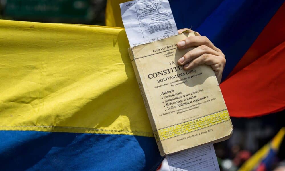 Fotografía de archivo del 17 de agosto del 2024 de una persona sosteniendo un libro de la constitución de Venezuela y una copia de actas de votación durante una protesta en Caracas (Venezuela). EFE/ Miguel Gutiérrez