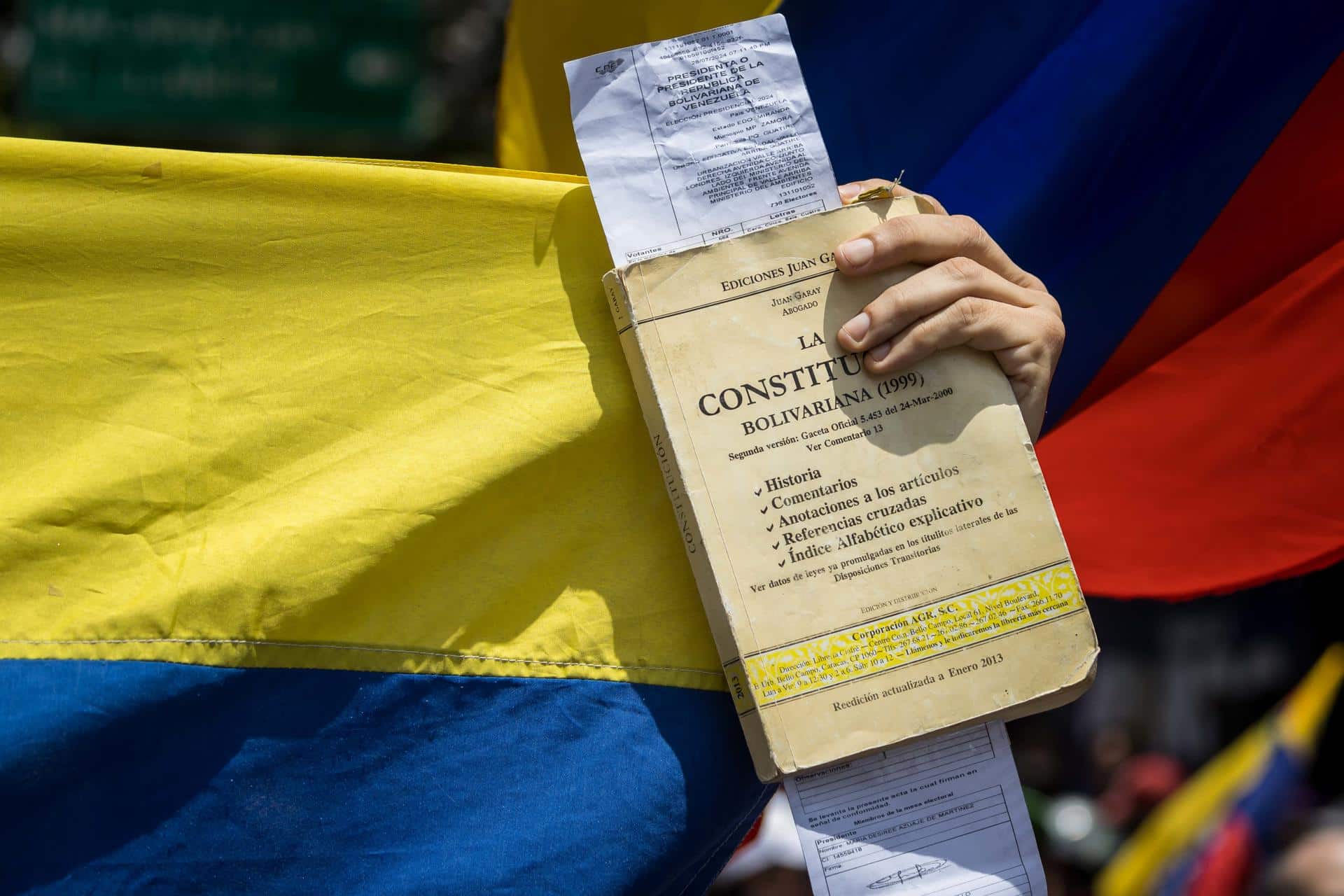 Fotografía de archivo del 17 de agosto del 2024 de una persona sosteniendo un libro de la constitución de Venezuela y una copia de actas de votación durante una protesta en Caracas (Venezuela). EFE/ Miguel Gutiérrez