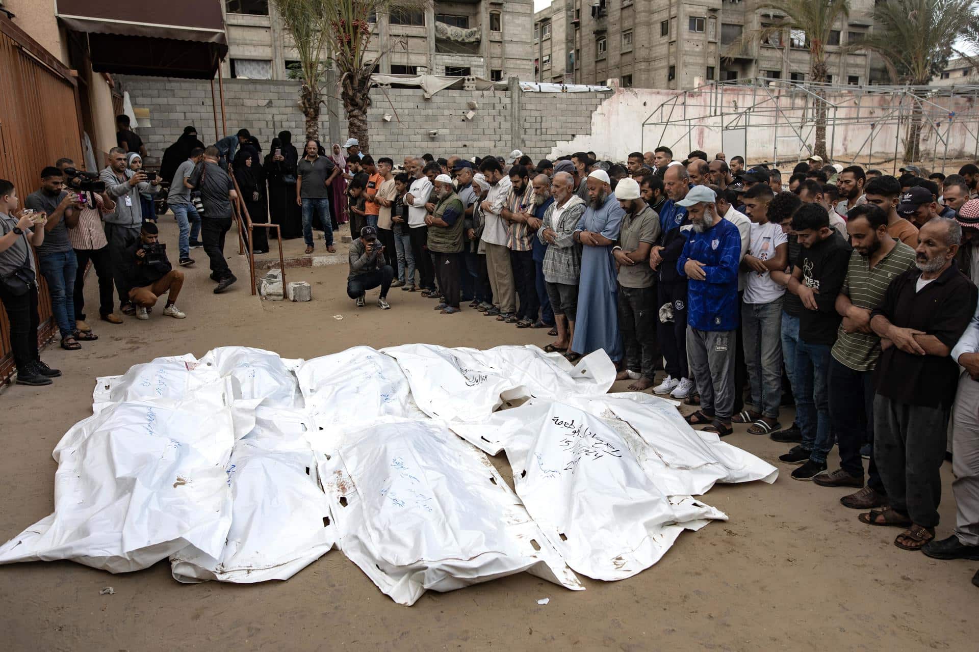 Palestinos rezan junto a los cadáveres de los miembros de una familia muertos en un ataque aéreo israelí en el sur de la Franja de Gaza, el 15 de octubre de 2024. EFE/EPA/HAITHAM IMAD