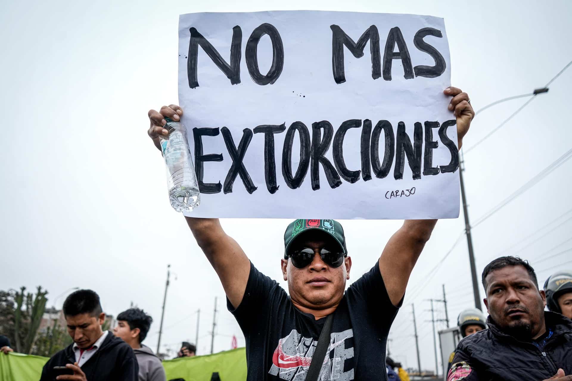 Un hombre sostiene un cartel durante una jornada de paro de transportadores, este jueves, en la ciudad de Lima (Perú). EFE/STR