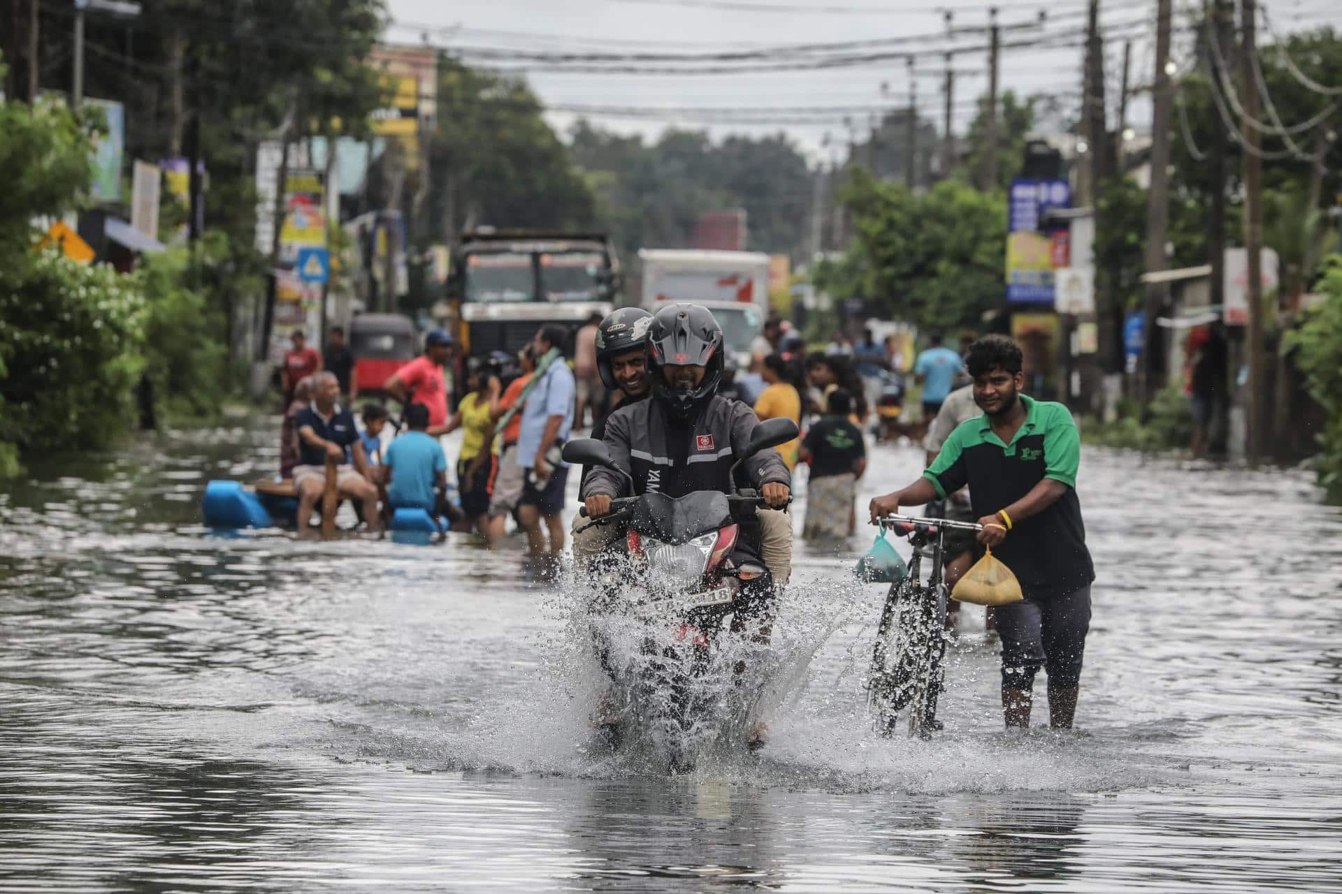 Víctimas de las inundaciones de Sri Lanka caminan por una carretera inundada después de fuertes lluvias en el suburbio de Colombo, Sri Lanka, este lunes. EFE/ Chamila Karunarathne