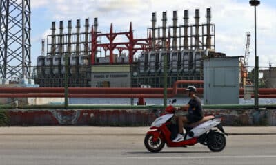 Un hombre en una moto eléctrica pasa frente a una de las plantas de generación eléctrica que permanece este domingo, en el puerto de La Habana (Cuba). EFE/ Ernesto Mastrascusa