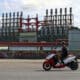 Un hombre en una moto eléctrica pasa frente a una de las plantas de generación eléctrica que permanece este domingo, en el puerto de La Habana (Cuba). EFE/ Ernesto Mastrascusa