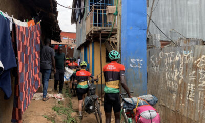 El grupo de la caravana de bicicletas atravesando una de las callejuelas de Kibera, un asentamiento informal situado en Nairobi, para llegar hasta la casa de la ONG Kings and Queens of Kibera. EFE/ Cristina Ondó Nieto