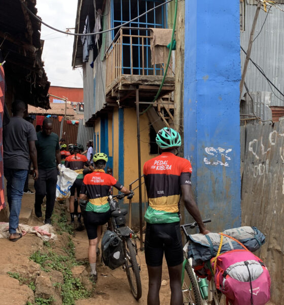 El grupo de la caravana de bicicletas atravesando una de las callejuelas de Kibera, un asentamiento informal situado en Nairobi, para llegar hasta la casa de la ONG Kings and Queens of Kibera. EFE/ Cristina Ondó Nieto