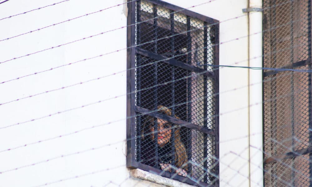 La expresidenta interina de Bolivia, Jeanine Añes (20019-2020), observa desde una ventana este lunes, en el centro de orientación femenina de Miraflores, en La Paz (Bolivia). EFE/ Gabriel Márquez