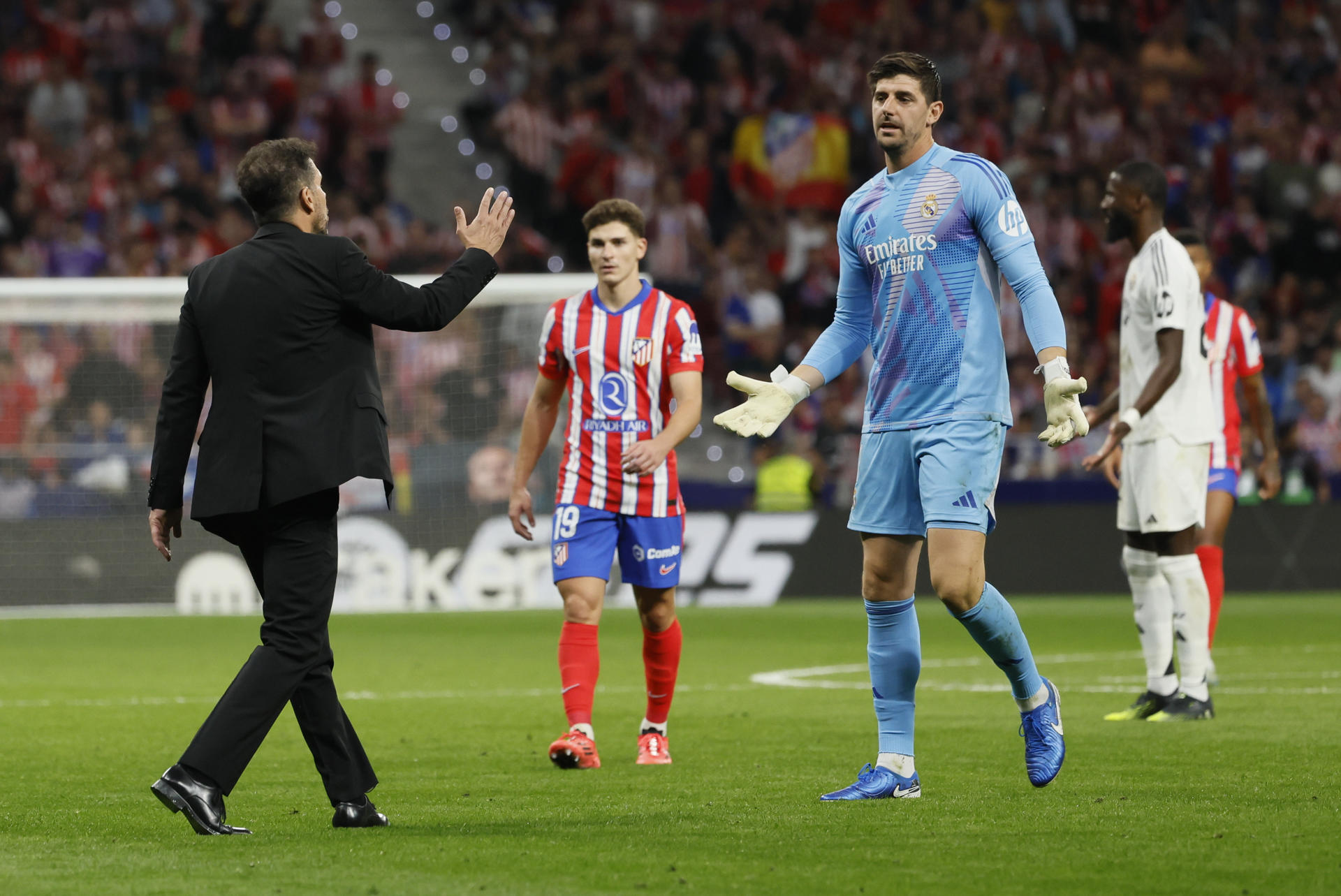 El portero del Real Madrid Thibaut Courtois (d) conversa con el entrenador del Atlético, Diego Simeone (i), durante el partido de la LaLiga EA Sports que Atlético de Madrid y Real Madrid en el estadio Civitas Metropolitano. EFE/Ballesteros