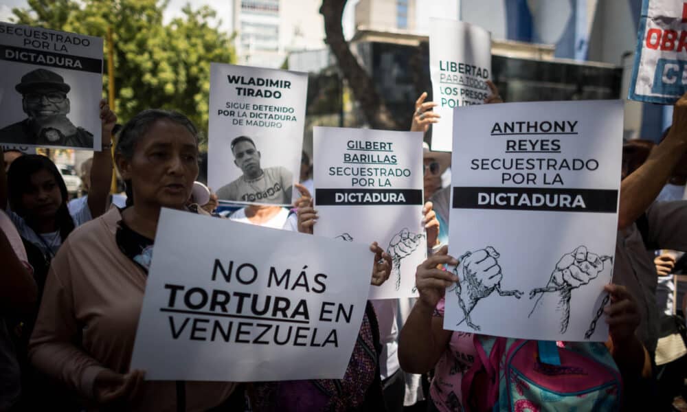 Fotografía de archivo de personas con carteles que muestran imágenes de detenidos durante una manifestación frente a la sede del Ministerio de Servicio Penitenciario, en Caracas. EFE/ Miguel Gutierrez