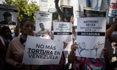 Fotografía de archivo de personas con carteles que muestran imágenes de detenidos durante una manifestación frente a la sede del Ministerio de Servicio Penitenciario, en Caracas. EFE/ Miguel Gutierrez