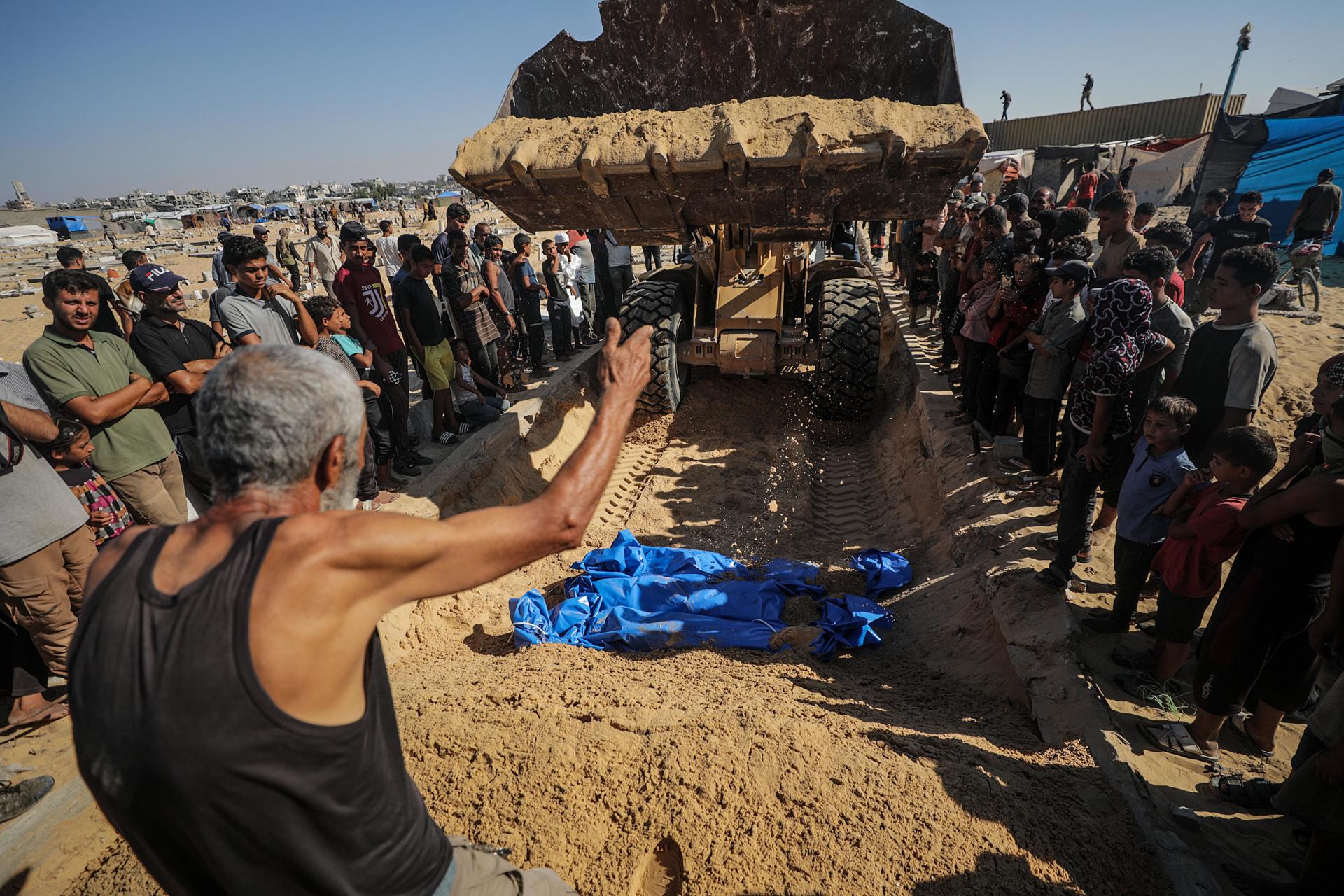 Varias personas asisten al entierro masivo de víctimas de bombardeos israelíes en el cementerio palestino de Jan Yunis. EFE/ Mohammed Saber