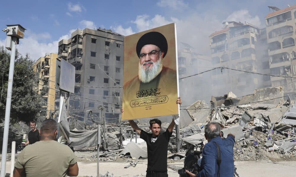 Un partidario de Hizbulá sostiene este miércoles una pancarta con la imagen de Hassan Nasrallah, junto a los escombros de un edificio completamente destruido en Dahieh, un suburbio del sur de Beirut controlado por Hizbulá. EFE/EPA/JOAO RELVAS