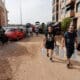 Varias personas con botellas de agua caminan entre los vehículos destrozados en la región valenciana de Paiporta a causa de las fuertes lluvias causadas por la DANA. EFE/Manu Bruque