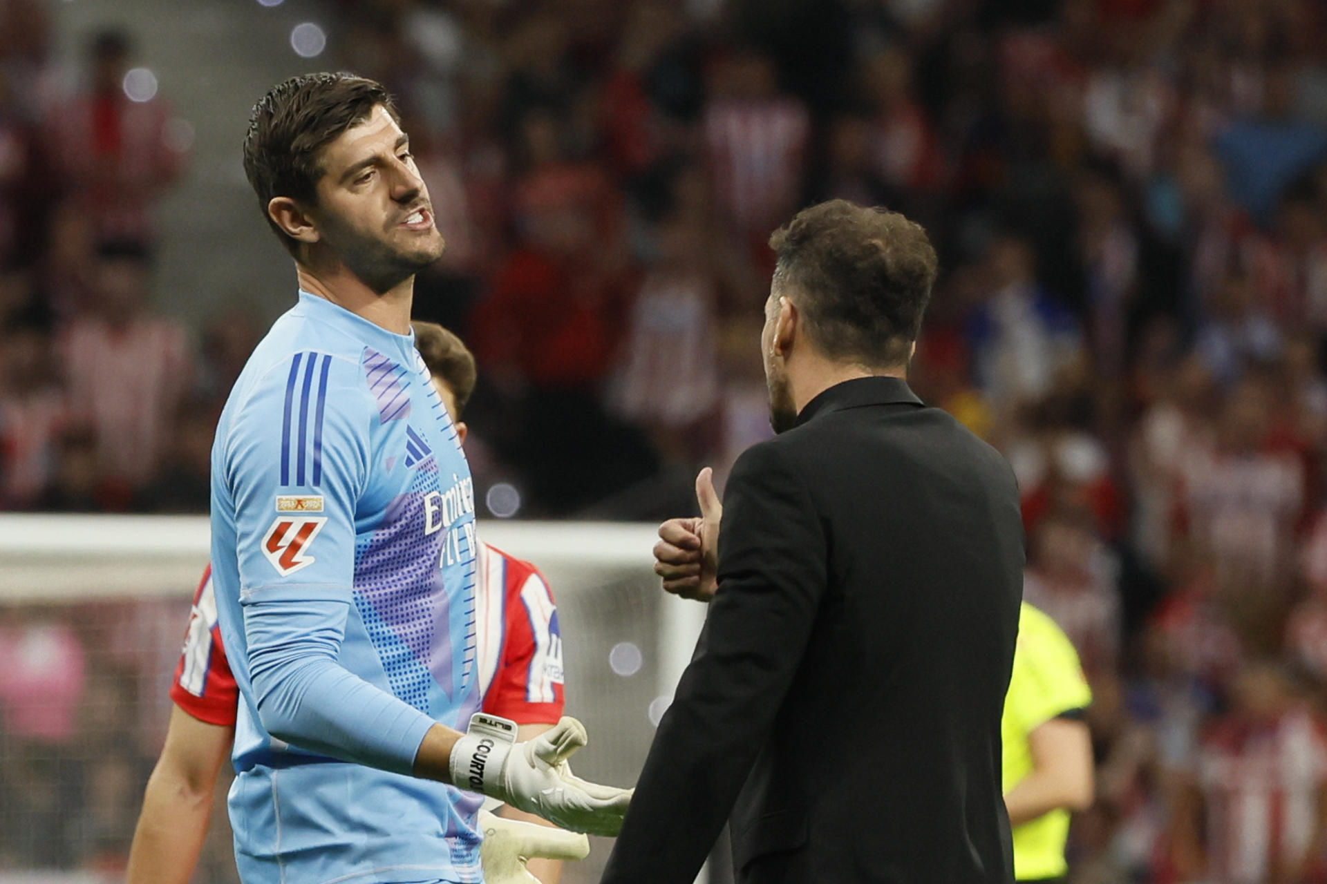 El portero del Real Madrid Thibaut Courtois (i) conversa con el entrenador del Atlético, Diego Simeone, durante en el estadio Civitas Metropolitano. EFE/Ballesteros