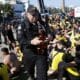 Un integrante de la policía incauta botellas con licor a los fanáticos del Peñarol de Uruguay, luego de ser detenidos en la playa de Pontal en Río de Janeiro. EFE/ André Coelho